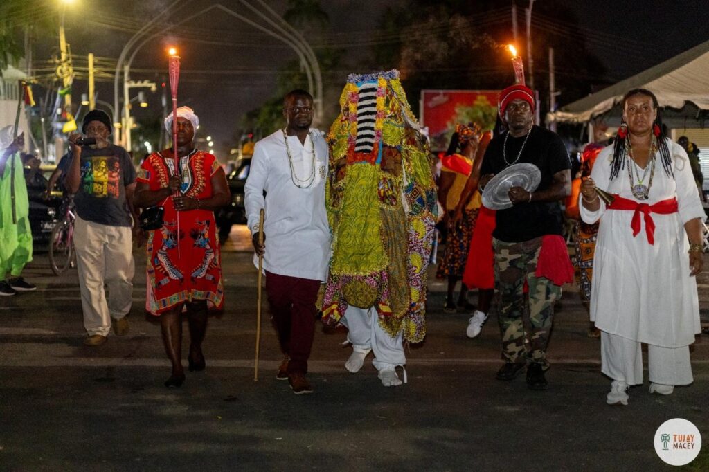 “𝐄𝐠𝐮𝐧𝐠𝐮𝐧 is a Yoruba traditional masquerade danced once a year to call forth and pay respect to the ancestors and to bring forth blessings and strength.” From Libation Walk, Georgetown, Guyana, July 31, 2025. Photograph by Joshua Tujay Macey.